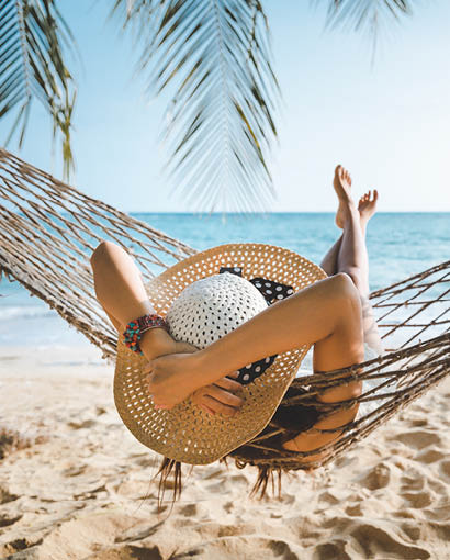 ECCU member relaxing in a hammock on a sunny beach, enjoying peace of mind and financial freedom.